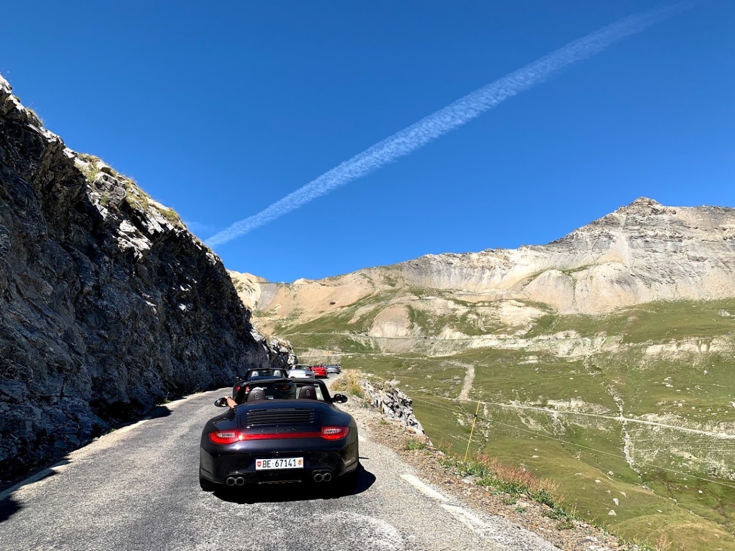 Black 911 cabrio on an Alpine mountain pass with dramatic peaks